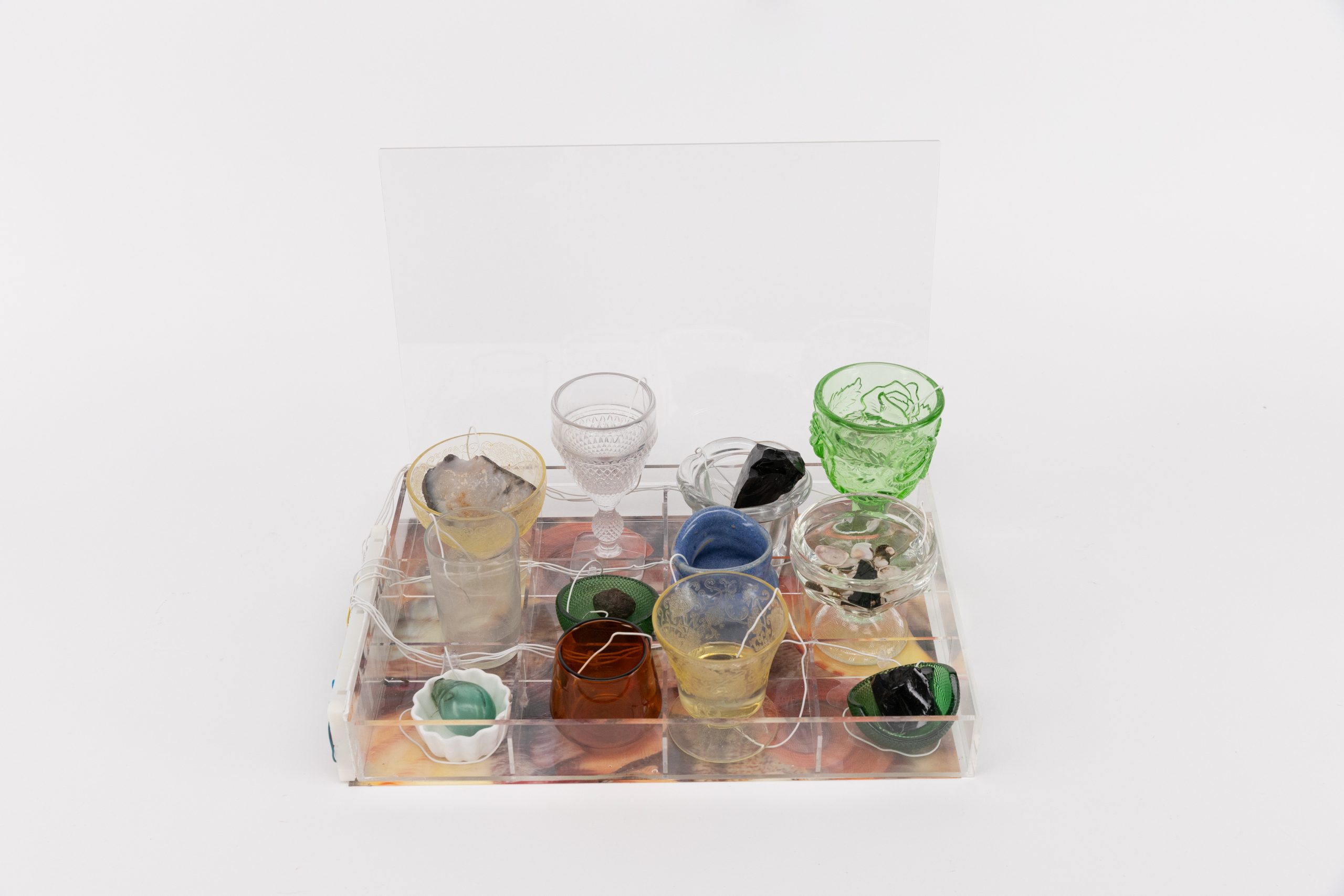 A tray with various glasses, seashells, and strings